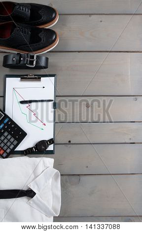 Businessman work outfit on grey wooden background. White shirt with black tie watch belt oxford shoes planchette and calculator. Back to work. Copy space frame. Set of mans fashion and accessories.