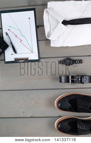 Businessman work outfit on grey wooden background. White shirt with black tie watch belt oxford shoes planchette and calculator. Back to work. Copy space frame. Set of mans fashion and accessories.