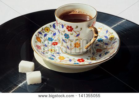 Nive day with music concept. Old vinyl plate and cup of coffee with sugar on it.