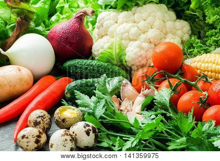 Fresh vegetables in drops of water quail eggs parsley and lettuce lying on a wooden table