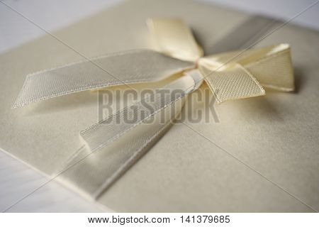 Squared silver envelope with pearly ribbon and topknot as an example of typical wedding invitation and wedding announcement cover letter