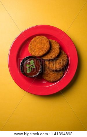 Indian chat item aloo or aalu tikki or tikiya or fried potato cake also known as ragda patties served with tomato ketchup, selective focus