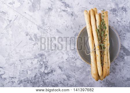 Fresh homemade crispy bread sticks with thyme and sea salt on a gray concrete background with fresh herbs. selective focus