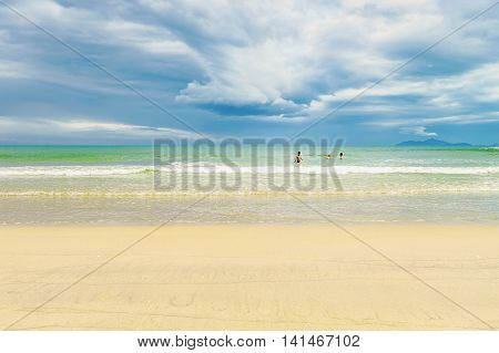Danang, Vietnam - February 20, 2016: Tourists in the sea at the China Beach in Danang in Vietnam. It is also called Non Nuoc Beach. South China Sea and Marble Mountains on the background.
