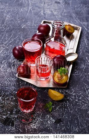 Transparent plum drink in a glass on a dark background. Selective focus.