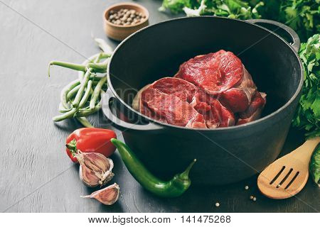 Beef in a cast iron pan cooking ingredients meat and season vegetables stylized photo