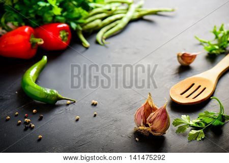 Dark table with culinary ingredients, focus on a garlic