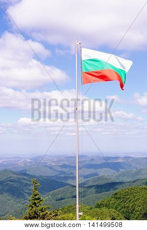 National Flag of Bulgaria with Green Mountains and Blue Sky in the Background. Location: near Shipka Memorial at Shipka Pass.