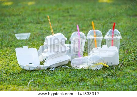 foam and plastic food container on grass field - environmental problems