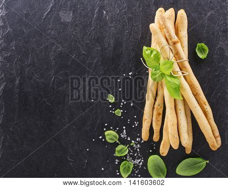 Fresh homemade crispy bread sticks with thyme and sea salt on a black background with fresh herbs. selective focus