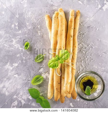 Fresh homemade crispy bread sticks with thyme and sea salt on a gray concrete background with fresh herbs. selective focus