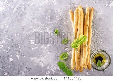 Fresh homemade crispy bread sticks with thyme and sea salt on a gray concrete background with fresh herbs. selective focus