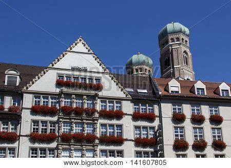 MUNICH, GERMANY - AUGUST 29, 2015: The Hirmer house with its beautiful decoration is the largest men's fashion house in the world in the background are the towers of the Frauenkirche (Cathedral of Our Dear Lady