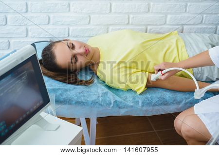 Female doctor examines girl patient with ultrasound in medical center.