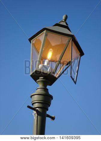 Broken hooligans street lamp.  Streetlight burning during the day as a symbol of waste,  losses and vandalism.
