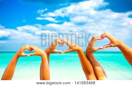 Summer holidays concept. Beautiful Happy young family father, mother and little son making heart shape with their hands over sea background. Tanning together. Vacation concept. Tourism