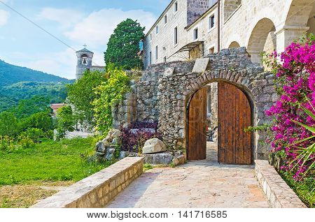 The wooden gate surrounded by flowers leads to the living side of Podmaine Monastery Budva Montenegro.