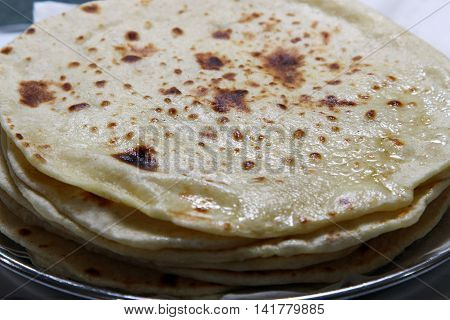A close up of a stack of buttered Kulcha