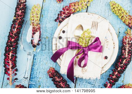 Tableware with violet flowers and silverware on the wooden background