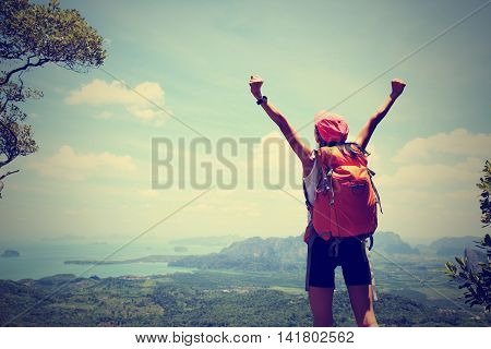 cheering woman hiker open arms at mountain peak