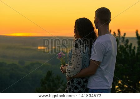 romantic couple look on sunset on country outdoor, beautiful landscape and bright yellow sky, love tenderness concept, young adult people
