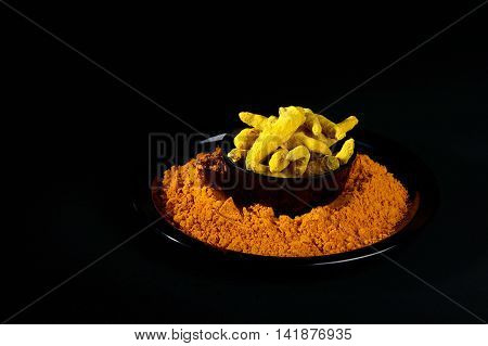 Turmeric powder and roots or barks on black background