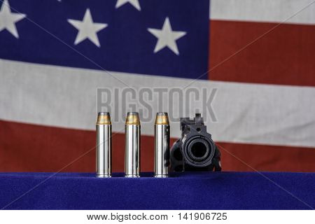 three bullets and 357 magnum revolver on blue with american flag background