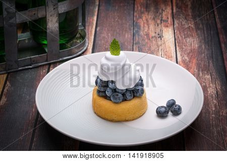 Fresh blueberries on a small cake with whipped cream