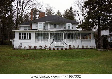 WEQUETONSING, MICHIGAN / UNITED STATES - DECEMBER 22, 2015: A large elegant white home, with a wraparound porch and a balcony, on Beach Road in Wequetonsing, Michigan.