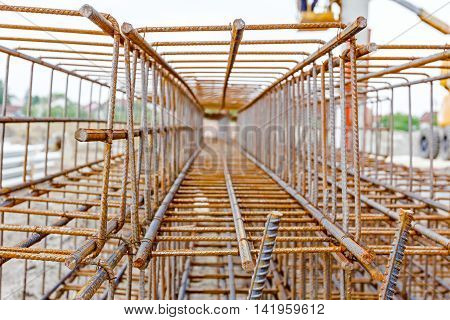 View perspective trough cage skeleton of reinforcing steel bar at construction site.