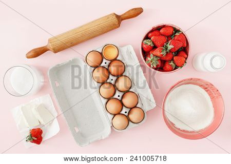 Flat Lay Raw Ingredients For Cooking Strawberry Pie Or Cake On Pink Background  (eggs, Flour, Milk, 