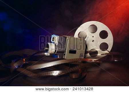 Retro 8 Mm Movie Camera With A Reel Of Film In Smoke. Dark Background