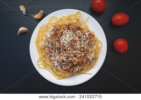 Appetizing Spaghetti In A Plate With Bolognese Sauce On A Dark Background, Garlic And Tomatoes