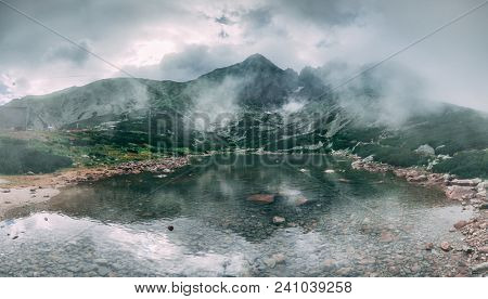 The fairy tale misty landscape the mountain Kalnate pleso lake surrounded by the mighty Tatras. Tatranska Lomnica, Slovakia. Ideal background in grey shades for the collages and illustrations.