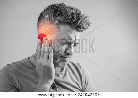 Male Having Ear Pain Touching His Painful Head Isolated On Gray Background
