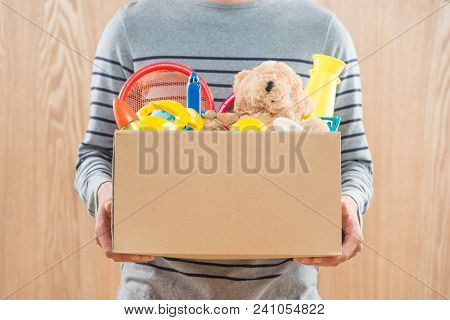 Male Volunteer Holding Donation Box With Old Toys.
