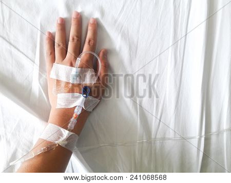 Patient Hand With The Tube Of Normal Saline Infusion On White Cloth Background