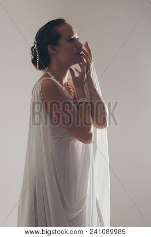 Girl In White And With Raised Hands, Attached To The Floor Dresses. The Bride In A Dress In Greek St