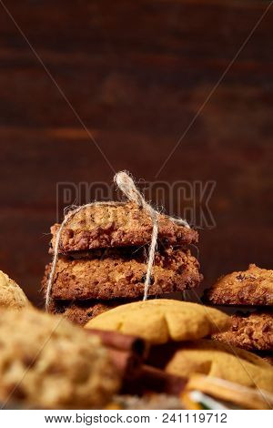 Conceptual Composition With Assortment Of Cookies, Cinnamon Sticks Bunch And Dried Oranges On A Wood