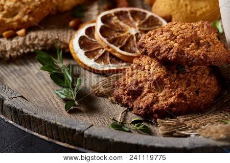 Conceptual Composition With Assortment Of Cookies, Cinnamon Sticks Bunch And Dried Oranges On A Wood