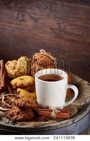Conceptual Festive Composition With A Cup Of Hot Tea, A Large Set Of Cookies, Cinnamon Sticks Bunch 