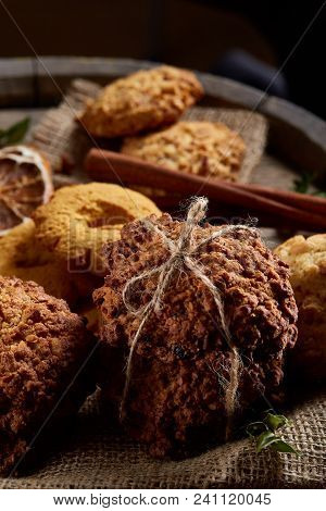Conceptual Composition With Assortment Of Cookies, Cinnamon Sticks Bunch On A Wooden Barrel Over Rus