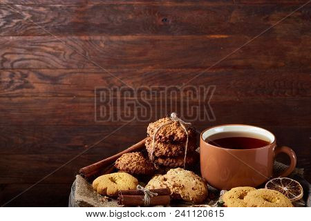 Festive Composition With A Mug Of Hot Tea, Assortment Of Cookies, Cinnamon Sticks Bunch And Dried Or