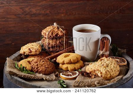 Conceptual Festive Composition With A Cup Of Hot Tea, A Large Set Of Cookies, Cinnamon Sticks Bunch 
