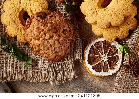 Conceptual Composition With Assortment Of Cookies, Cinnamon Sticks Bunch And Dried Oranges On Burlap