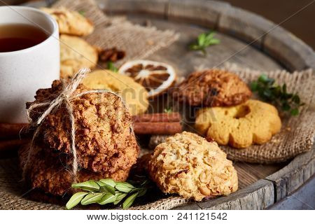 Conceptual Festive Composition With A Cup Of Hot Tea, A Large Set Of Cookies, Cinnamon Sticks Bunch 