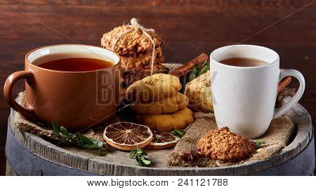 Conceptual Festive Composition With Two Cups Of Hot Tea, A Large Set Of Cookies, Cinnamon Sticks Bun