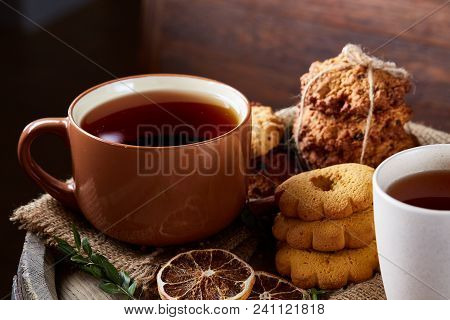 Conceptual Festive Composition With Two Cups Of Hot Tea, A Large Set Of Cookies, Cinnamon Sticks Bun