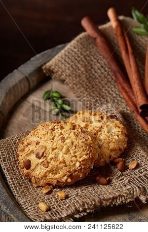 Conceptual Composition With A Couple Of Cookies, Cinnamon Sticks Bunch On A Wooden Barrel Over Rusti