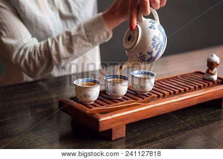 Cropped Shot Of Woman Pouring Tea In Traditional Chinese Teaware.